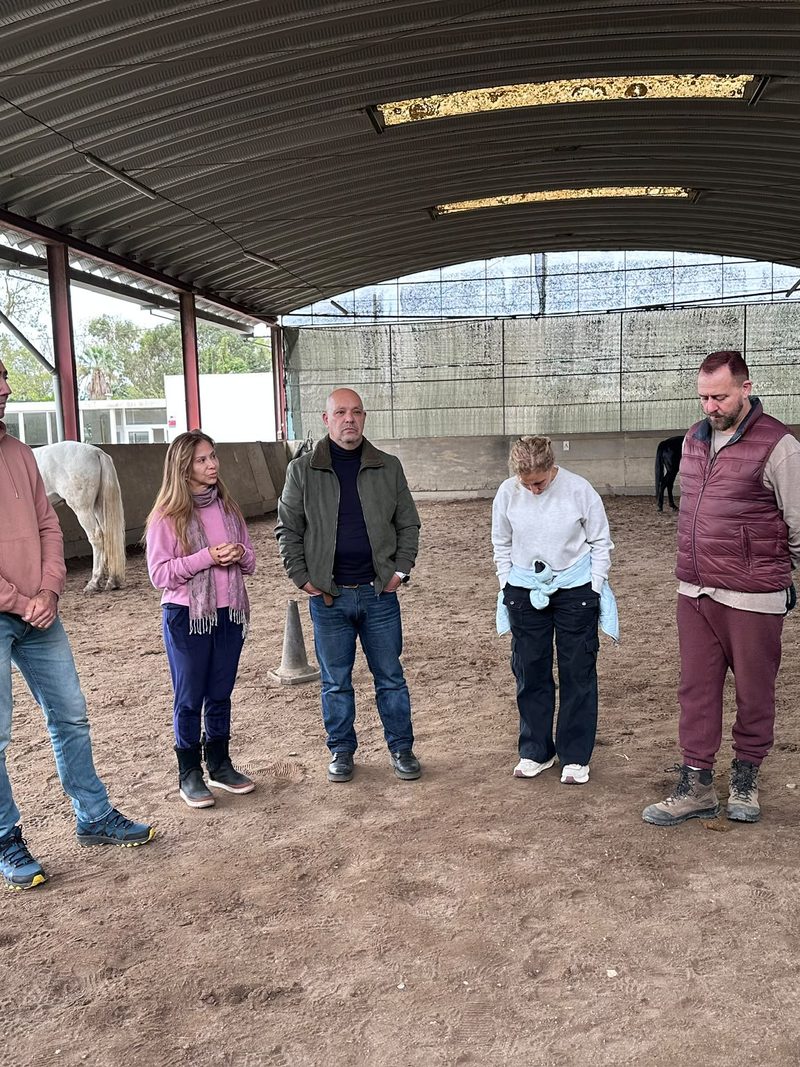 A group of adults standing in an arena during a workshop