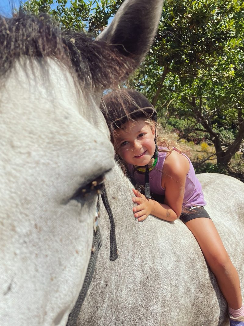 A child resting her face against a white horse