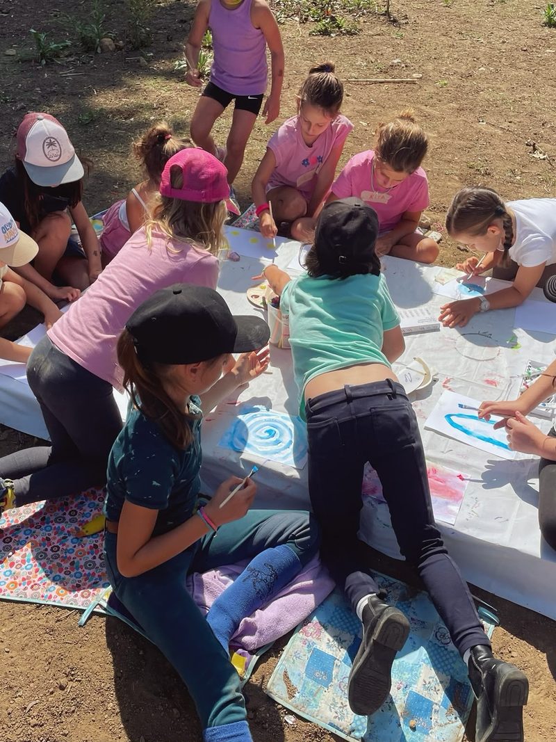 Children working together on a large painting outdoors
